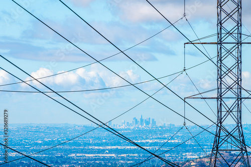 Los Angeles skyline behind power tower and power lines on a blue cloudy day