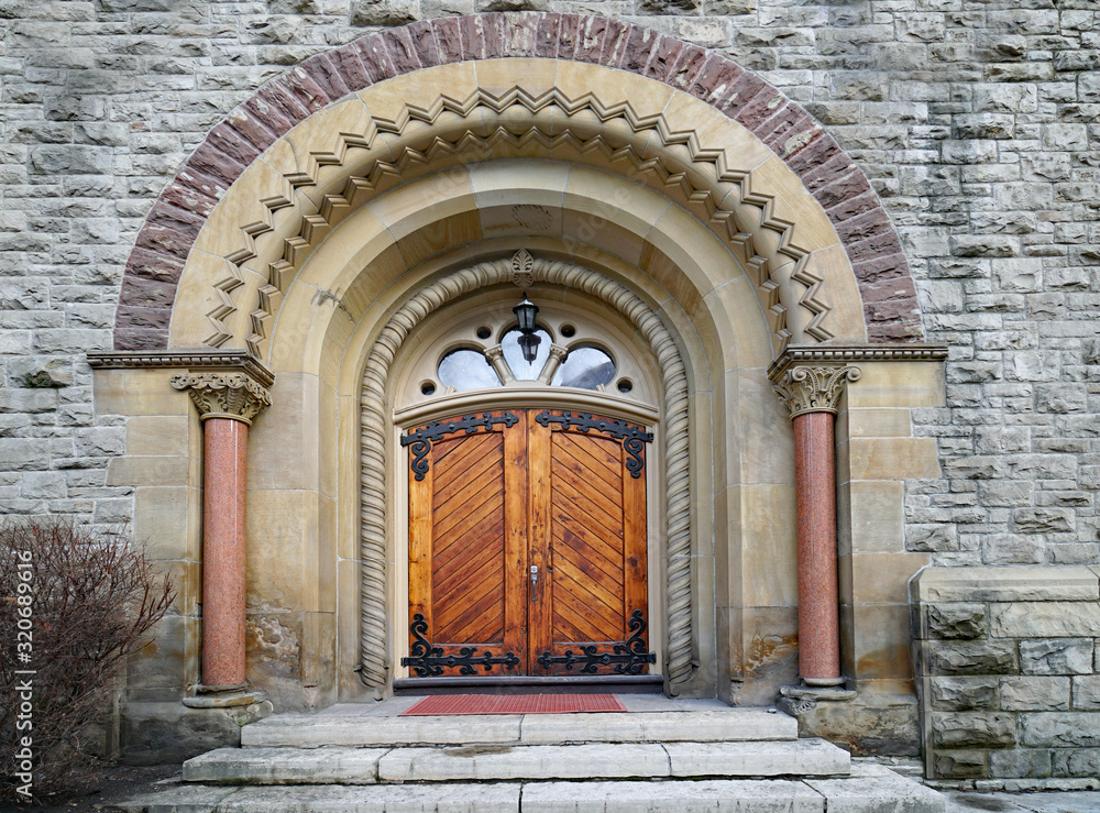 Fototapeta premium old wooden door with iron reinforcements on stone building