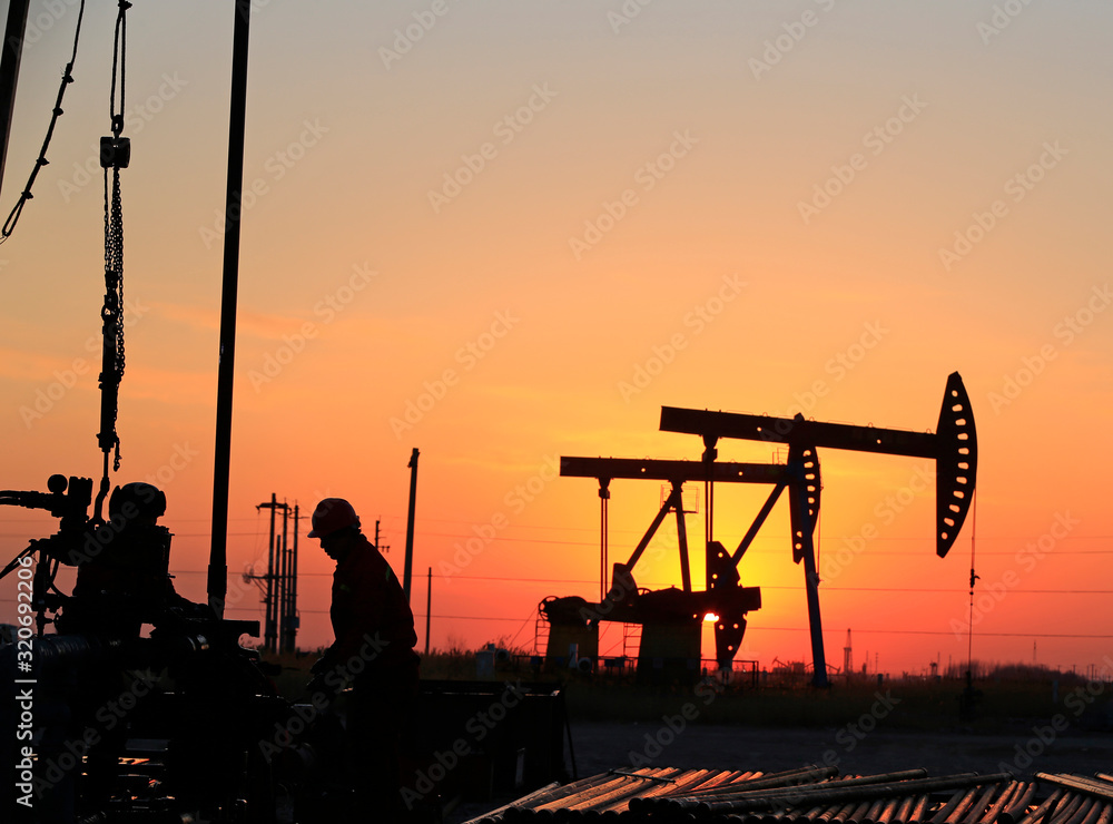 The oil workers are working in the sunset silhouettes