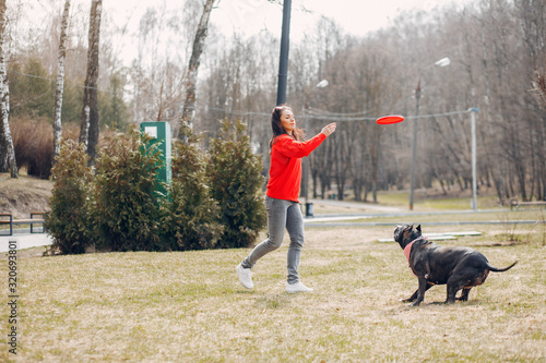 Sports woman in a red sweater. Woman in a summer park. Lady with a dog © hetmanstock2