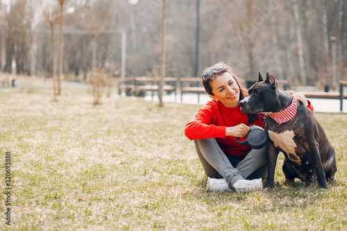 Sports woman in a red sweater. Woman in a summer park. Lady with a dog