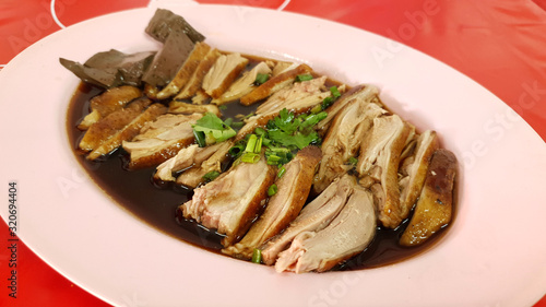 Asian style fresh sliced duck meat strewed with special black soy sauce on pink plate