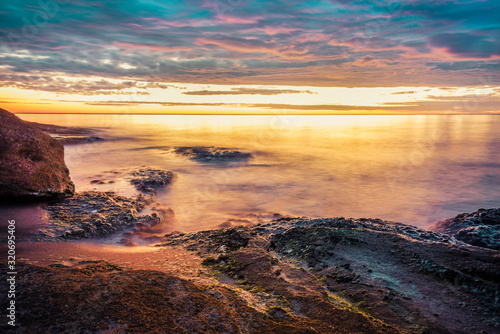 Picturesque sunrise over a rocky beach. © dil_ko