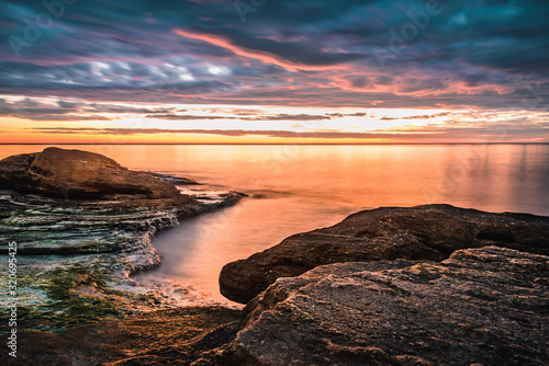 Picturesque sunrise over a rocky beach.