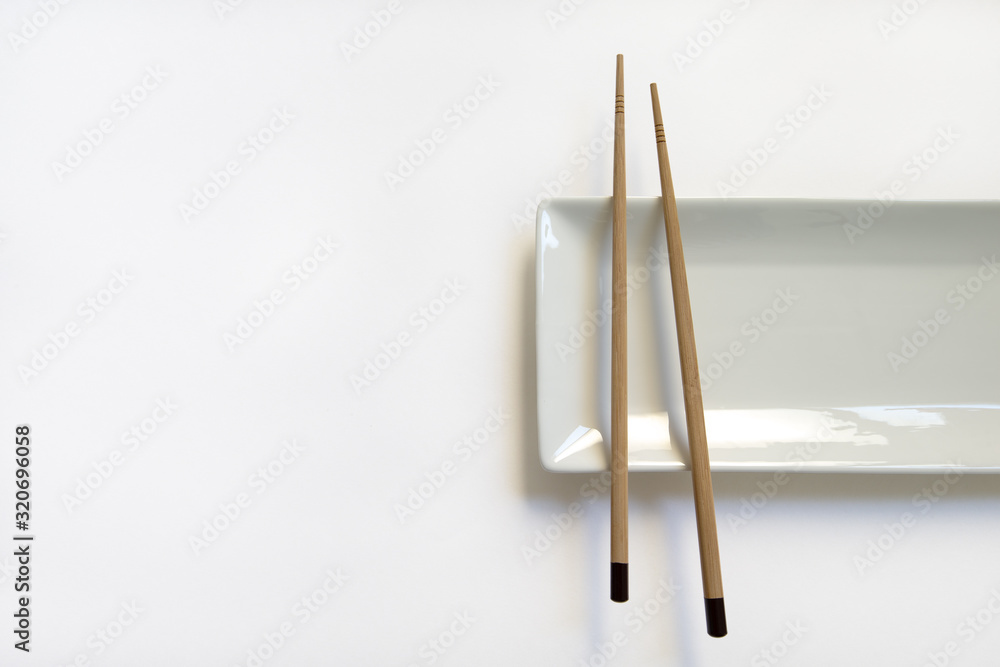  Wooden pairs of chopsticks and ceramic dish on white background. rectangular plate isolated. top view. 