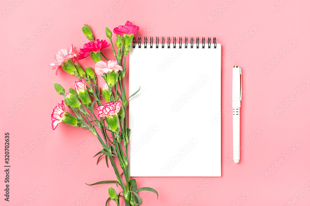 colorful bouquet of different pink carnation flowers, white notebook, pen on pink background Top view Flat lay Holiday card 8 March, Happy Valentine's day, Mother's day concept Mock up