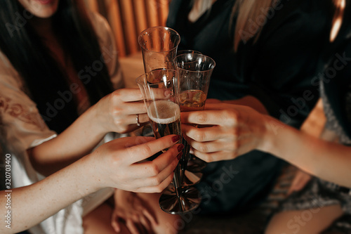 group of girls at a bachelorette party raise glasses of champagne with bubbles, light-skinned hands of girls, a hand with a wedding ring. warm tinting.
