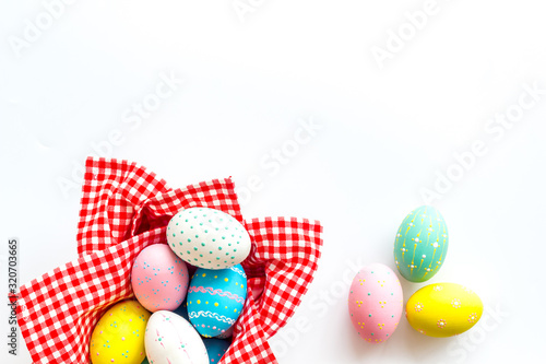 Easter eggs painted in basket on white desk top-down copy space