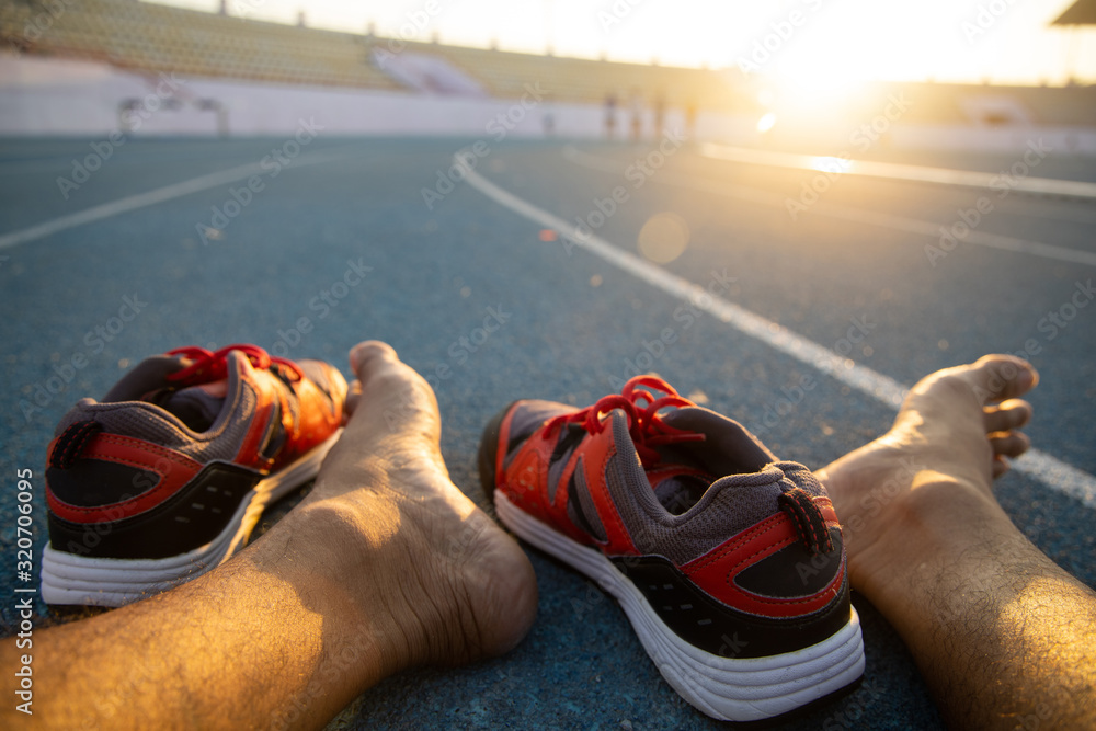 Men's feet are preparing to wear shoes to run on the stadium. Stock