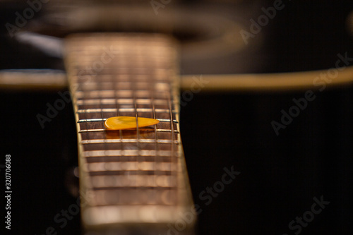 An acoustic guitar with a pick - close up on frets