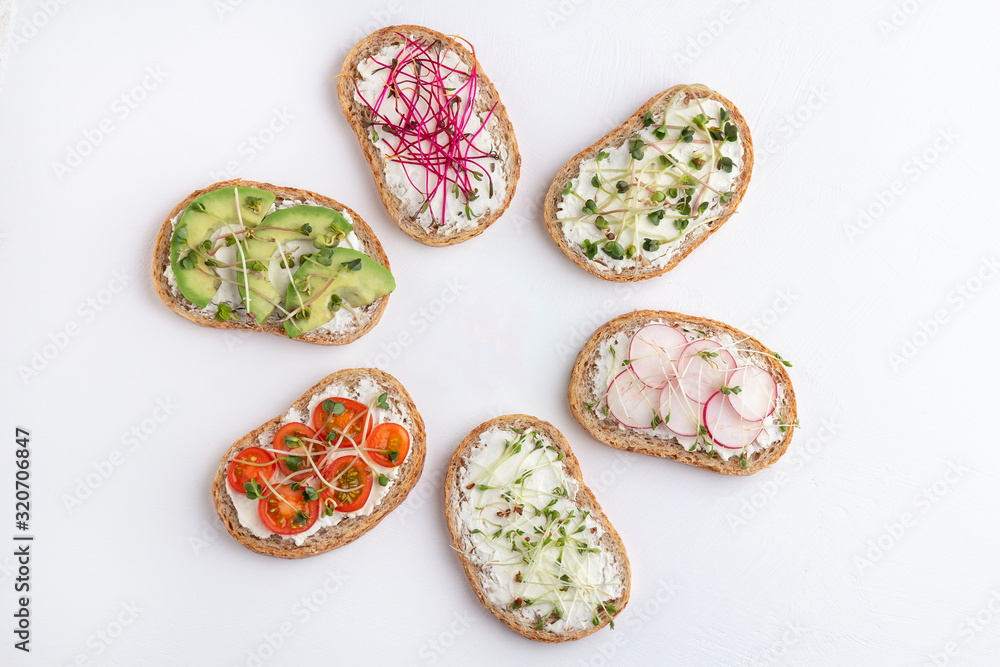 Fototapeta Different sandwiches with microgreens and vegetables on a white background