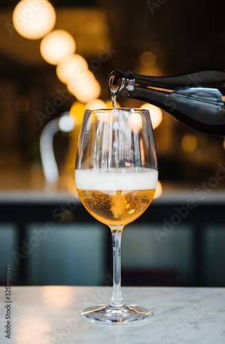 Glass of hard cider being poured in a bar setting photo