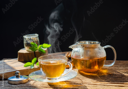  hot tea is poured from the kettle into a kettle with tea leaves redcurrant mandarin orange lemon,rosemary, mint.,hot food and healthy meal concept