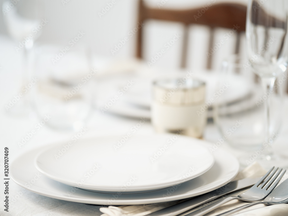 Beautiful table setting in white colors. Empty white plates. Set table for romantic dinner for two at home Beautiful table setting in white colors. Empty white plates. Set table for romantic dinner for two at home