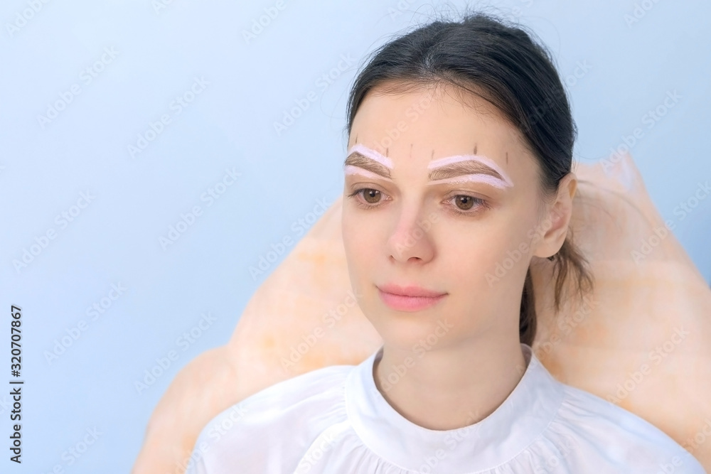 Portrait of woman with painted shape of eyebrows on face before tinting in beauty clinic. Girl is sitting and waiting cosmetologist. Preparing to painting eyebrow procedure, shaping brows. Portrait of woman with painted shape of eyebrows on face before tinting in beauty clinic. Girl is sitting and waiting cosmetologist. Preparing to painting eyebrow procedure, shaping brows.