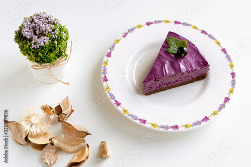 slice of cake with cream and fruits. Black currant cake. Food photo on a white background. High key. Berries and flowers. Raw desserts.