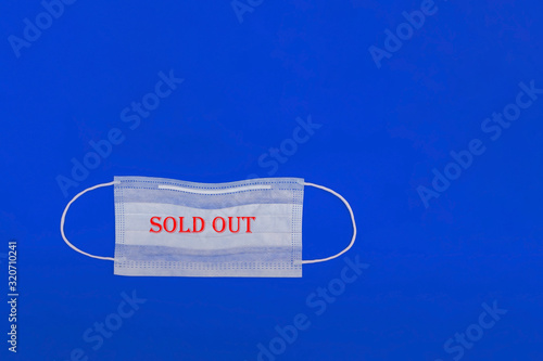 Medical mask with the inscription sold out on a blue background. Coronavirus 2019-nCov. Mers-Cov. Close-up.