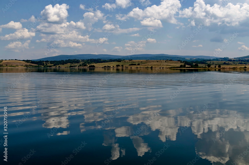 Natural reflection on Vlasina Mountain Lake and beautiful cloudy sky, Southeastern Serbia, Europe  