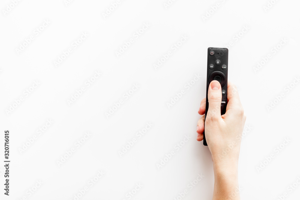 Watch TV concept. TV remote in hand on white background top-down copy space Watch TV concept. TV remote in hand on white background top-down copy space