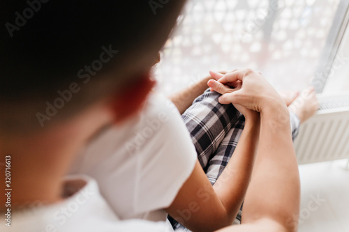 Dark-haired man holding hands with girlfriend during home photoshoot. Blissful married couple enjoying family day.