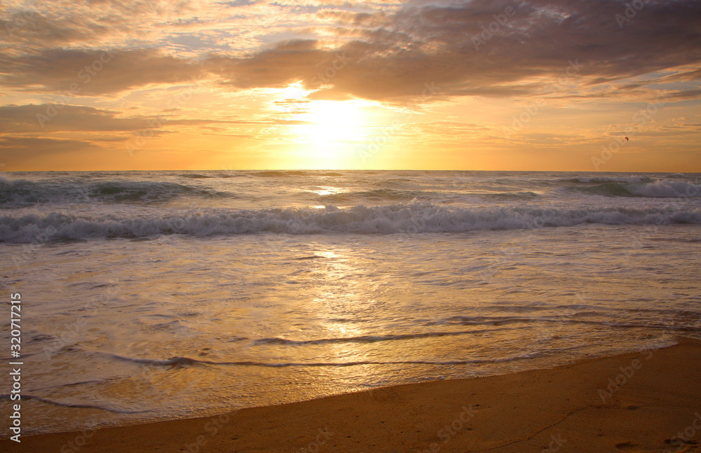 Beautiful sunset on tropical beach. The surf pounds the shore. Karon beach, Phuket, Thailand