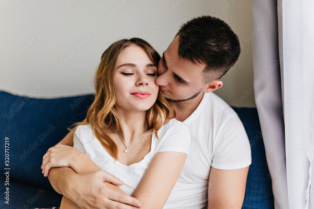 Spectacular girl in white t-shirt spending weekend with boyfriend. Joyful man kissing wife in morning. Spectacular girl in white t-shirt spending weekend with boyfriend. Joyful man kissing wife in morning.