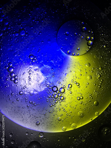 bubble oil on the water look like planet in the space  with colour full light in dark background.