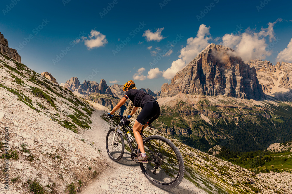 Cycling woman in Dolomites mountains landscape. Girl cycling MTB enduro trail track. Outdoor sport activity.