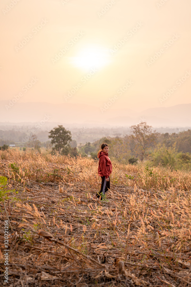 Young women travel to watch the sunset wearing a red sweater.