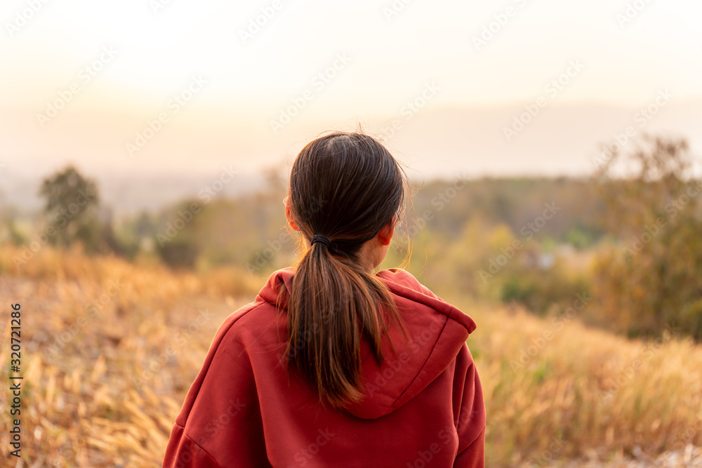 Young women travel to watch the sunset wearing a red sweater.