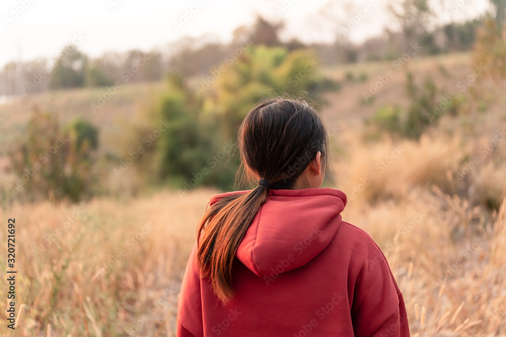 Young women travel to watch the sunset wearing a red sweater.