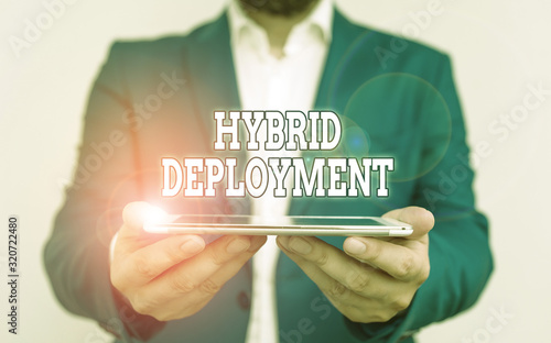 Text sign showing Hybrid Deployment. Business photo text a combination of onpremises applications or data Businessman holds laptop in his hand. Man holding mobile phone with touch screen photo