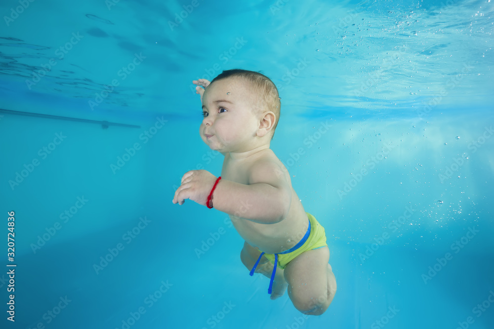boy learns to dive underwater in a swimming pool