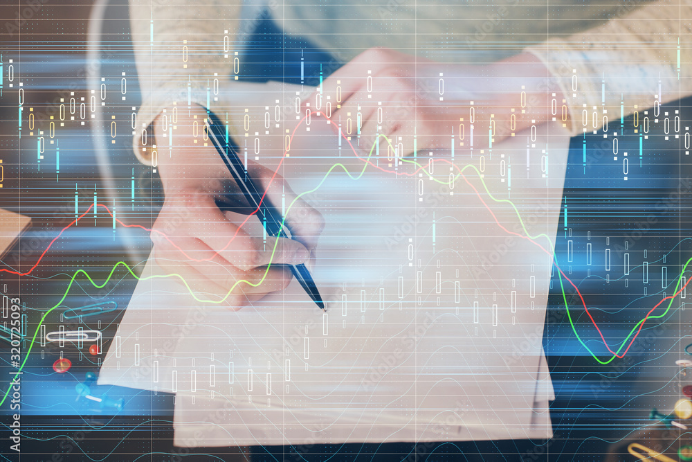 Hand taking notes in notepad. Forex chart holograms in front. Concept of research. Multi exposure Hand taking notes in notepad. Forex chart holograms in front. Concept of research. Multi exposure