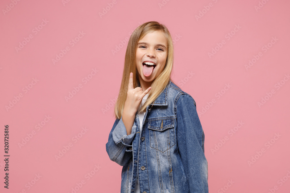 Little kid girl 12-13 years old in denim jacket isolated on pastel pink background children portrait. Childhood lifestyle concept. Mock up copy space. Showing tongue, depicting heavy metal rock sign. Little kid girl 12-13 years old in denim jacket isolated on pastel pink background children portrait. Childhood lifestyle concept. Mock up copy space. Showing tongue, depicting heavy metal rock sign.