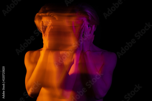 young handsome man naked torso. Closing face with hands. Long exposure artistic portrait. Orange and pink. dreamy drama artistic look. 