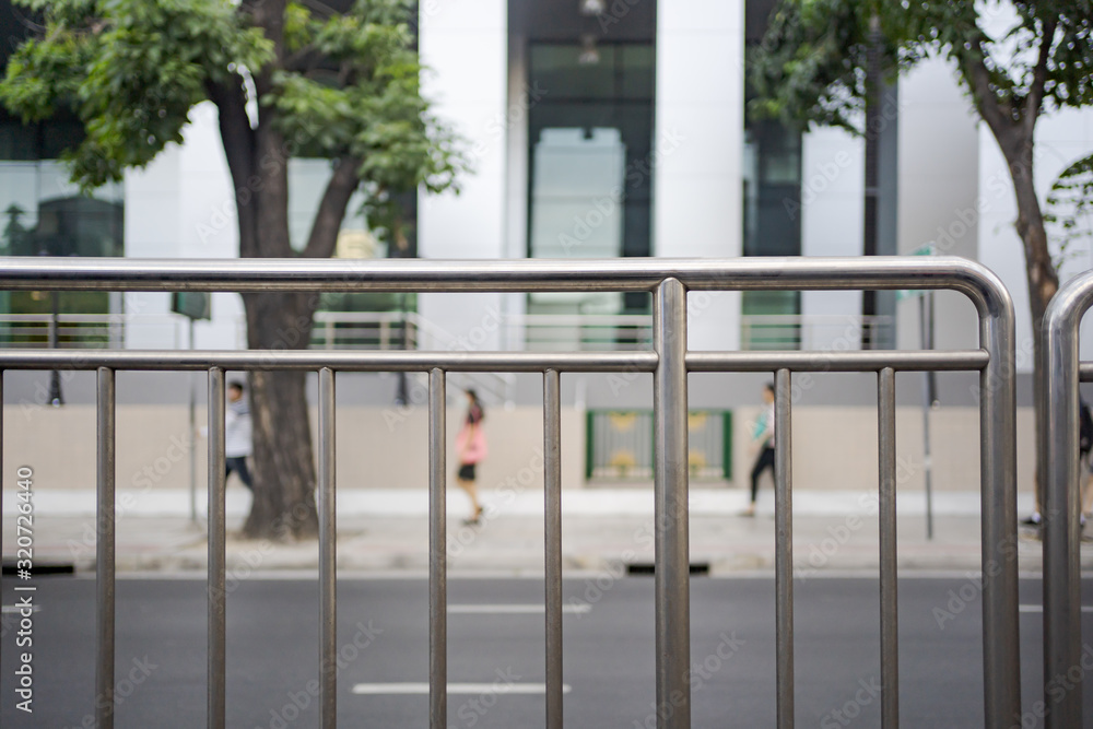 Pavement fence with pedestrian walking on clean footpath in the background Pavement fence with pedestrian walking on clean footpath in the background