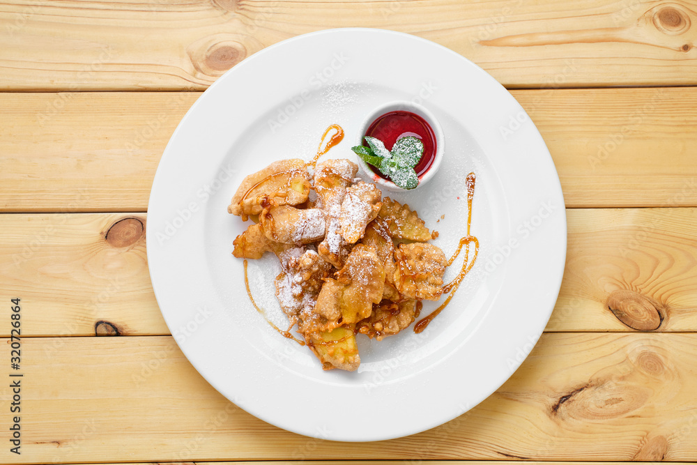 Top view of plate with deep fried fruits in breading served with caramel and strawberry jam Top view of plate with deep fried fruits in breading served with caramel and strawberry jam