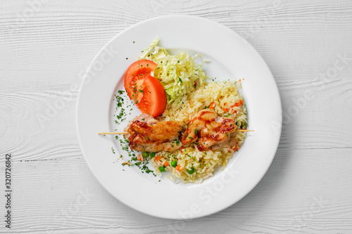 Top view of plate with chicken shashlik, rice with peas and cabbage salad
