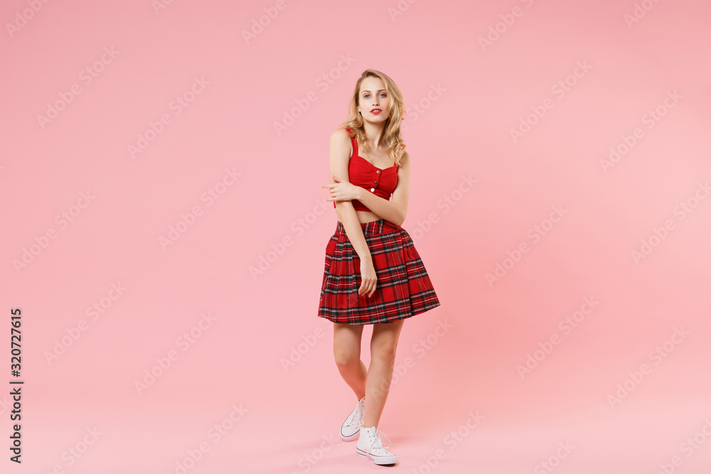 Stunning young blonde woman girl in red sexy clothes posing isolated on pastel pink wall background studio portrait. People sincere emotions lifestyle concept. Mock up copy space. Looking camera. Stunning young blonde woman girl in red sexy clothes posing isolated on pastel pink wall background studio portrait. People sincere emotions lifestyle concept. Mock up copy space. Looking camera.