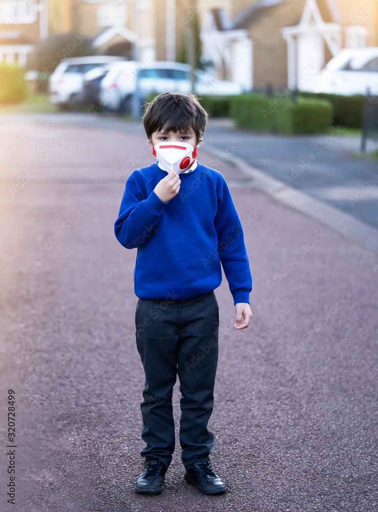 Kid wearing protective face mask for pollution or virus, Mixed race asian - caucasian 6 year old, Child wearing protection mask while walking to school, Concept for Corona or Coronava virus and pm 2.5 Kid wearing protective face mask for pollution or virus, Mixed race asian - caucasian 6 year old, Child wearing protection mask while walking to school, Concept for Corona or Coronava virus and pm 2.5