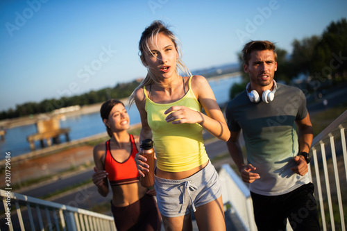 Fit happy friends jogging and running together outdoor in city