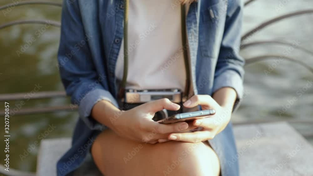 Close up of asian woman using smartphone devices sharing social media while sitting beside Chao Phraya River in Thailand on vacation summer. Close up of asian woman using smartphone devices sharing social media while sitting beside Chao Phraya River in Thailand on vacation summer.