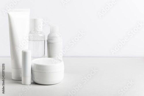 Obraz na płótnie Facial and body care cosmetics bottles composition on white background. Gel tube, lipstick, cream jar unbranded blank packages. Skincare female products advertising with light backdrop w salonie
