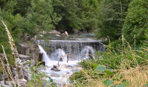 Kleiner Wasserfall mit Fokus auf Gräsern davor