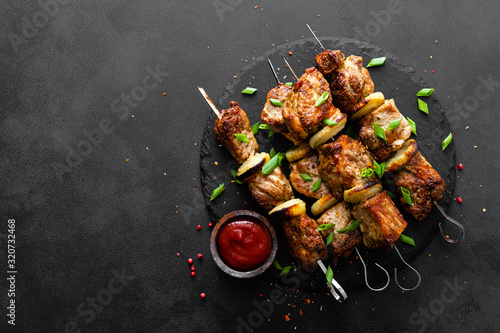 Grilled meat skewers, shish kebab on black background, top view