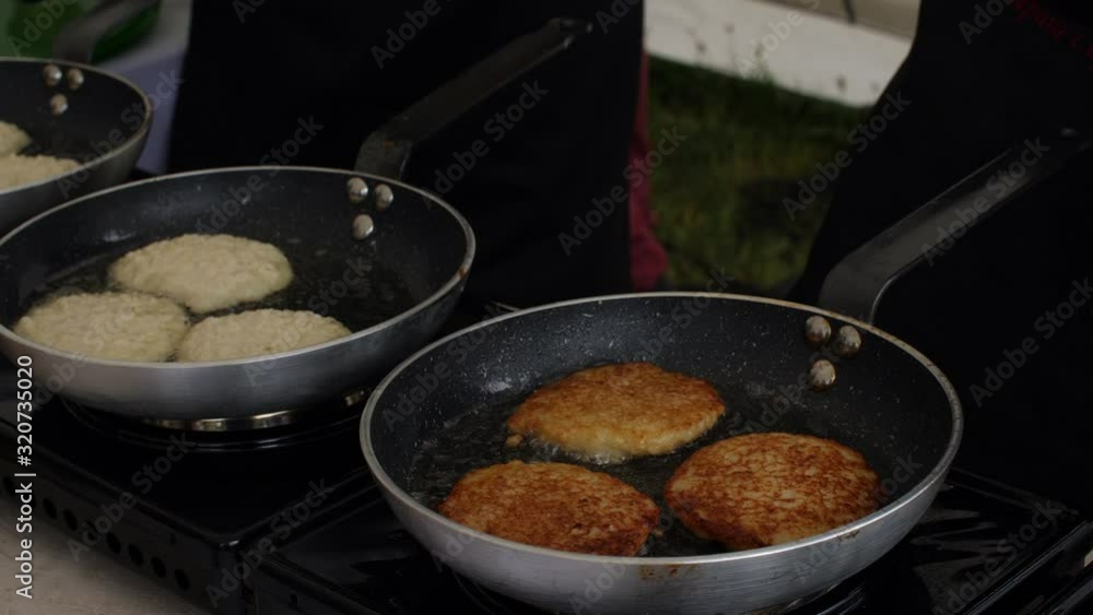 Close up of preparation of golden potato pancakes in frying pan. Street food concept. Life camera Close up of preparation of golden potato pancakes in frying pan. Street food concept. Life camera