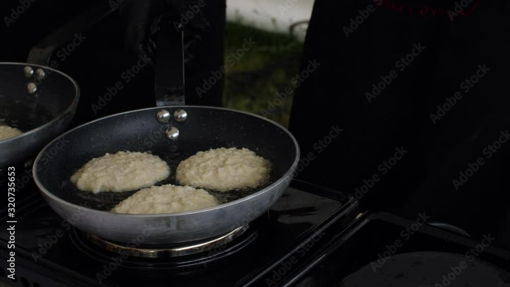 Close up of preparation of golden potato pancakes in frying pan. Street food concept. Life camera Close up of preparation of golden potato pancakes in frying pan. Street food concept. Life camera