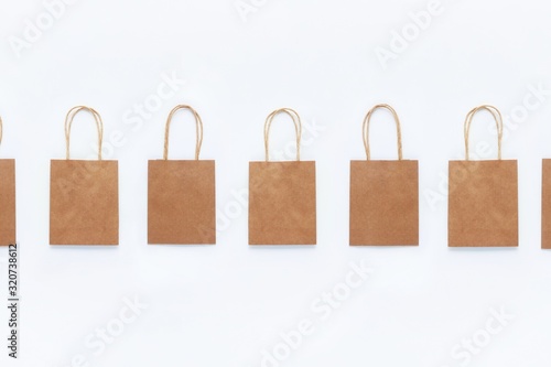 Brown craft bags for shopping on a white background in a row. The concept of zero waste, reasonable consumption, recycling, discounts. Top view, flat lay. Copy space for text.
