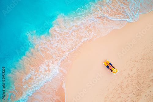 Aerial view of a woman on the beach in a bikini lying and sunbathing